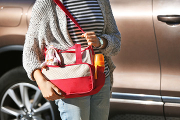 Woman with baby bag standing near a car