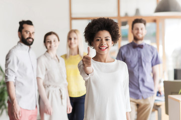 Obraz premium woman showing thumbs up over creative office team