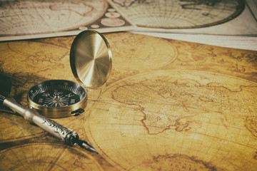 Old compass, fountain pen on ancient maps of the world. Nautical items .