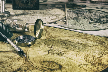 Old compass, fountain pen, and seashells on ancient maps of the world. Nautical items .