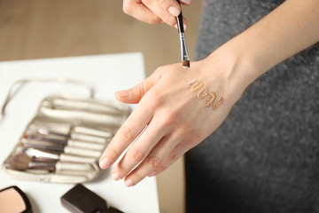 Female visagiste applying cosmetics onto hand