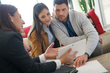 Real estate agent showing house project on tablet to clients