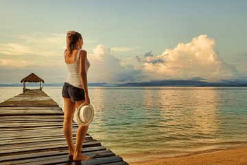 Lonely woman standing on pier and admires far islands in beautif