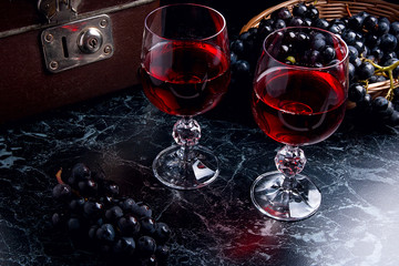 Glass of red wine on dark marble background. Cluster of blue gra
