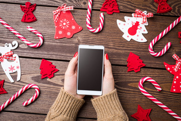 Woman holding smart phone over wooden table. Christmas background