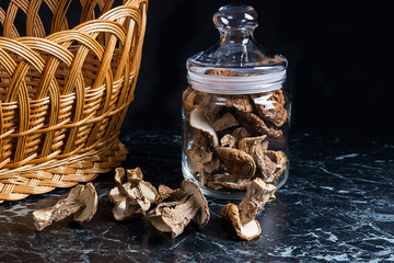 Dried wild mushrooms on black marble background.