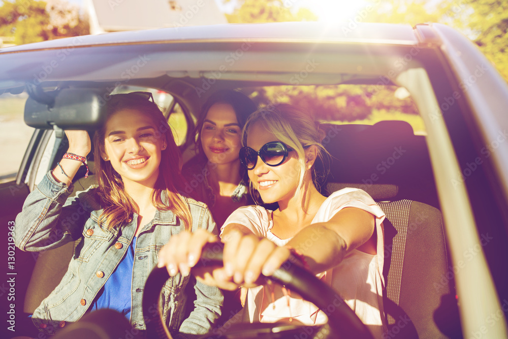 Wall mural happy teenage girls or young women driving in car