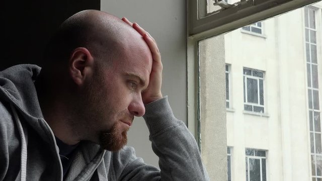 sad desperate and depressed young man near the window