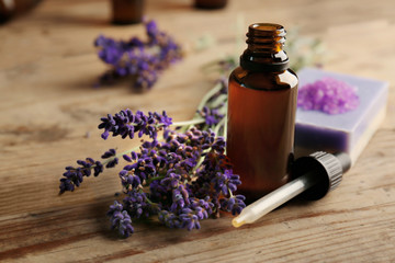 Fototapeta na wymiar Bottle with aroma oil and lavender flowers on wooden background