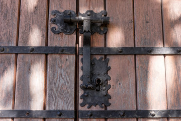 Closeup of an ornamental iron hinge on old wooden door