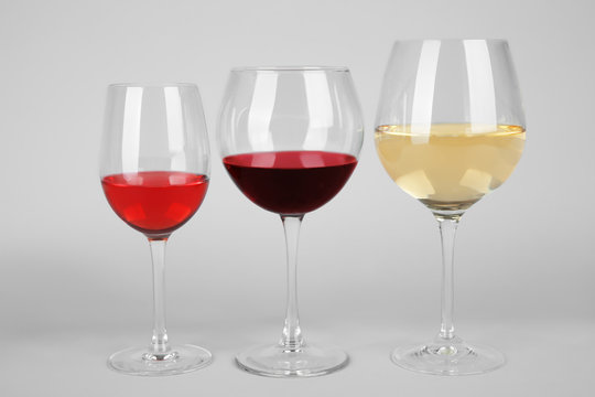 Three glasses with tasty wine on light background