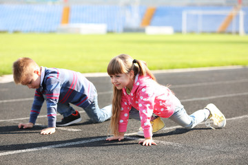 Little girl and boy in ready position to run on track