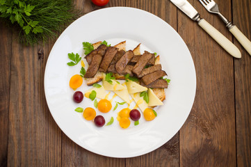 Sliced roast beef on toast, cheese, basil, berries, plum and Dutch sauce. Restaurant supply  a wooden background. Top view. Close-up