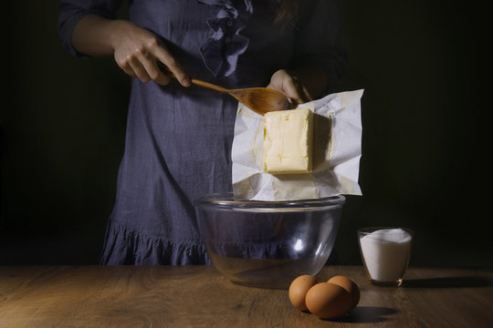 Women hands putting butter in bowl. Step of making cooking cake, preparing dough. Ingredients: butter, sugar, eggs.