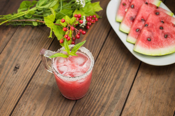 Fresh watermelon juice on a background of slices     wooden table. Close-up