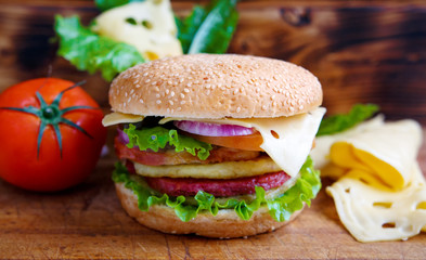 Burger with tomato and cheese on the table of the old village boards