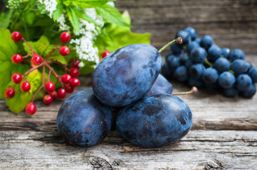 Plums with grapes on a wooden background. Top view. Close-up