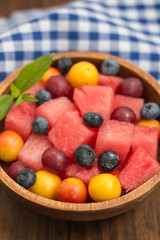 Fruit and berry salad of watermelon, blueberries, plums, currants, gooseberry, cherry plum. Wooden background. Top view. Close-up