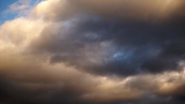 Clouds passing over sky. Dark clouds and golden light.