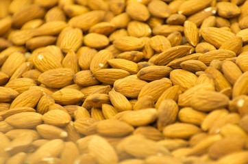 Heap of raw almonds nuts background