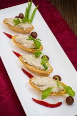 Forshmak, Jewish dish of chopped herring, baked with potatoes, sour cream, onions and peppers, referring to the starters. Filed in the tartlet on a rectangular plate. Wooden background. Close-up.