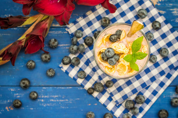 Blueberry Yogurt, cereal and a sprig of mint. Wooden blue background. Top view. Close-up