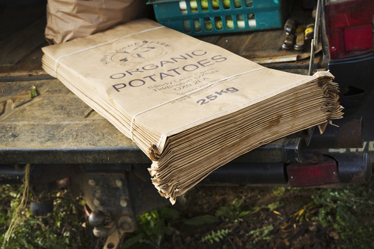 A heap of printed paper vegetable sacks on a farm wagon, labelled Organic Potatoes.