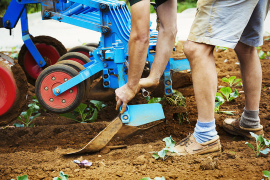 Man realigning a cultivator in a field.