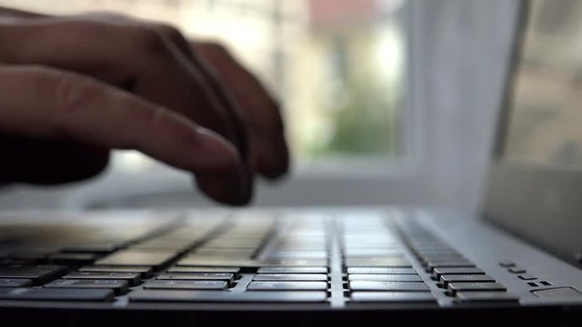 silhouette of male hands writing a document with a laptop 