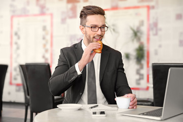 Young businessman working in cafe while having snack