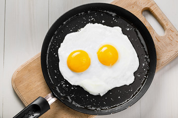 Fried eggs meal in a frying pan for delicious healthy breakfast. Traditional international breakfast food, top view.