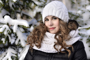 Girl in a white knitted hat for a walk in the winter forest