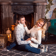 Merry Christmas. Young couple celebrating New Year at home. Man and a woman by the fireplace