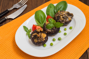 Stuffed champignon quail eggs with basil and tomatoes. Wooden background. Close-up