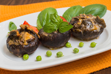 Stuffed champignon quail eggs with basil and tomatoes. Wooden background. Close-up