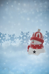 Snowman on a blue winter background. Falling snow and snowflakes.