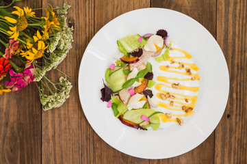 Salad of stewed meat, green, perepilinyh poached eggs, cucumbers, basil, plum and Dutch sauce with walnuts. Wooden background. Top view. Close-up