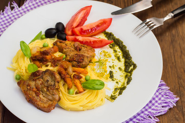 Tagliolini with meat in tomato sauce, olives and   spinach. Wooden background. Close-up. Top view