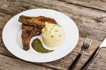 Pork steak on the bone grilled with mashed potatoes and spinach  herbs sauce. Wooden background. Close-up. Top view
