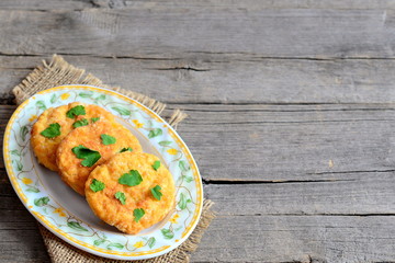 Fried pea burgers on a plate isolated on old wooden background with copy space for text. Homemade burgers made from dried peas and decorated with parsley leaves. Vegetarian high protein food. Closeup