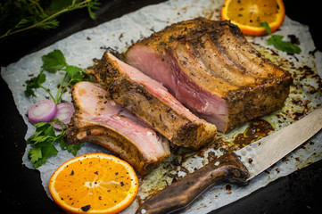 Baked pork ribs with sauce and basil on a black table. Top view. Close-up. Selective focus