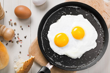 Petit-déjeuner rapide sain et traditionnel composé de deux œufs au plat servis sur une poêle à frire. Cuisine internationale simple, vue de dessus.