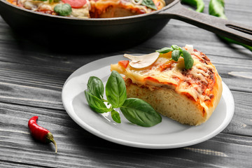 Plate with slice of tasty pizza on wooden table