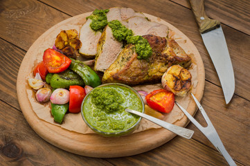 Meat with vegetables, grilled and served  Italian Salsa Verde sauce. Wooden rustic table. Close-up