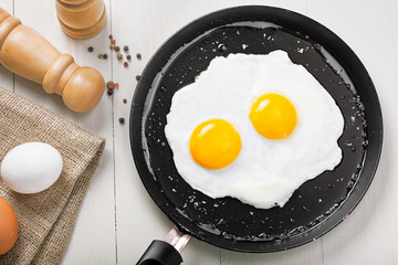 Healthy quick breakfast made of two fried eggs on a table. Traditional simple food on a frying pan for eating. Top view.