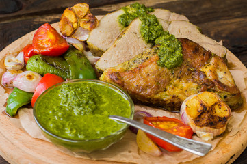 Meat with vegetables, grilled and served  Italian Salsa Verde sauce. Wooden rustic table. Close-up