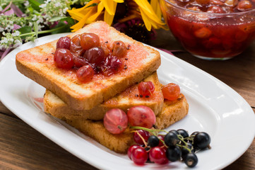 Toast with gooseberry jam. Wooden background  flowers. Top view. Close-up