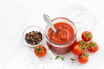 tomato sauce in a glass jar and white background, top view 
