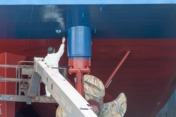 ein Mann streicht das Heck eines Schiffes im Trockendock