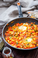 Shakshuka Breakfast of Fried Eggs, Tomatoes, Paprika, Red Hot Chili Pepper and Herbs in a Pan, Vertical View From Above